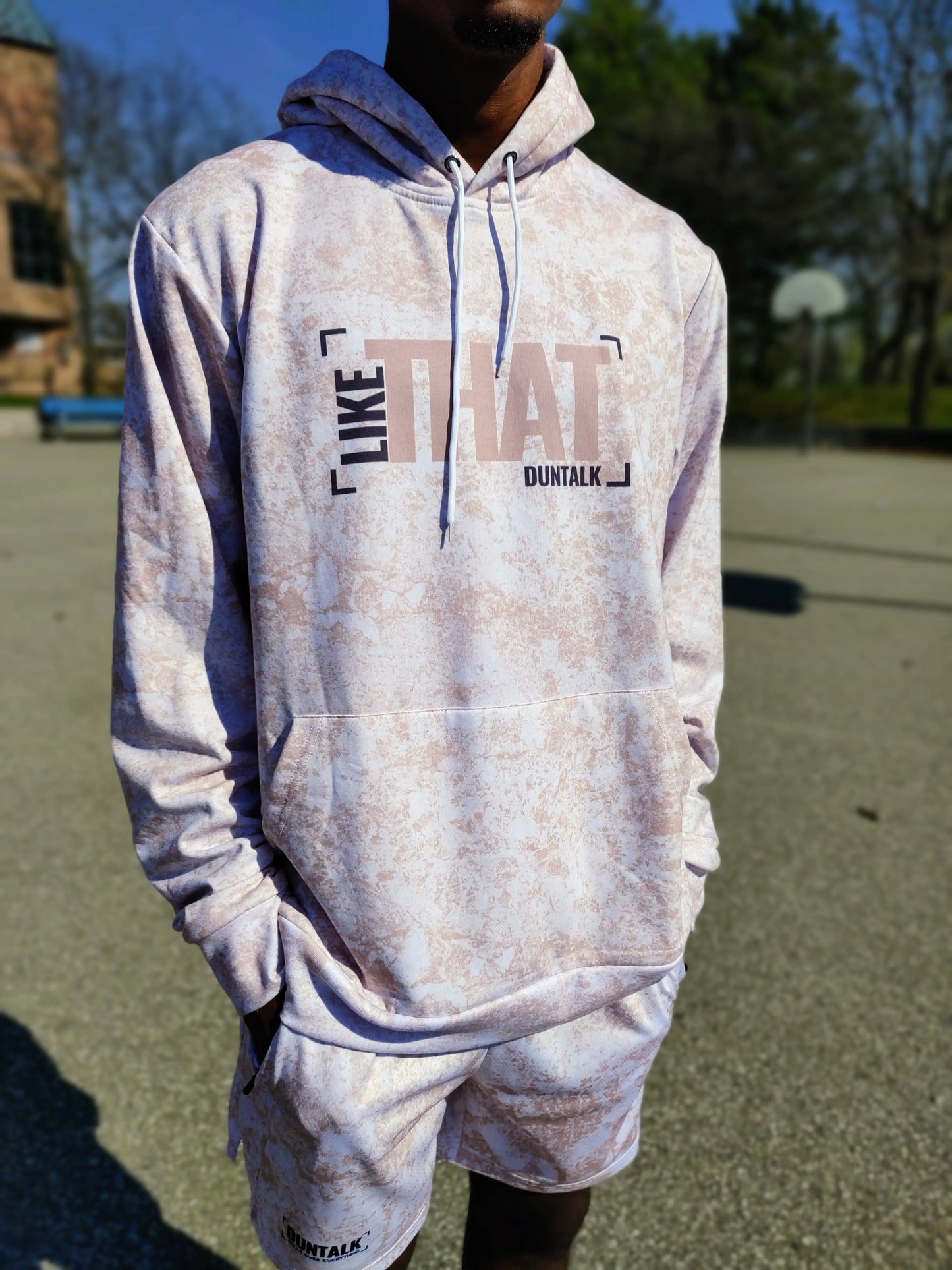 White sweater with pink mud design, hood and front pocket. Words on sweater say "Like That Duntalk" in black and pink font