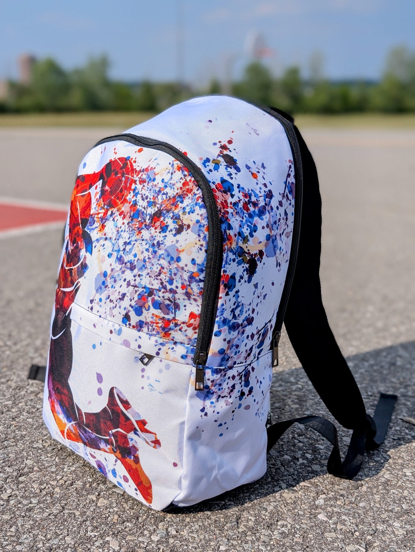 Backpack with colorful splatter design on a concrete surface from the side