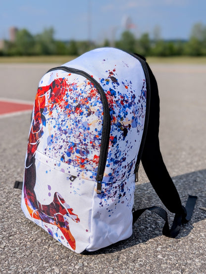 Backpack with colorful splatter design on a concrete surface from the side