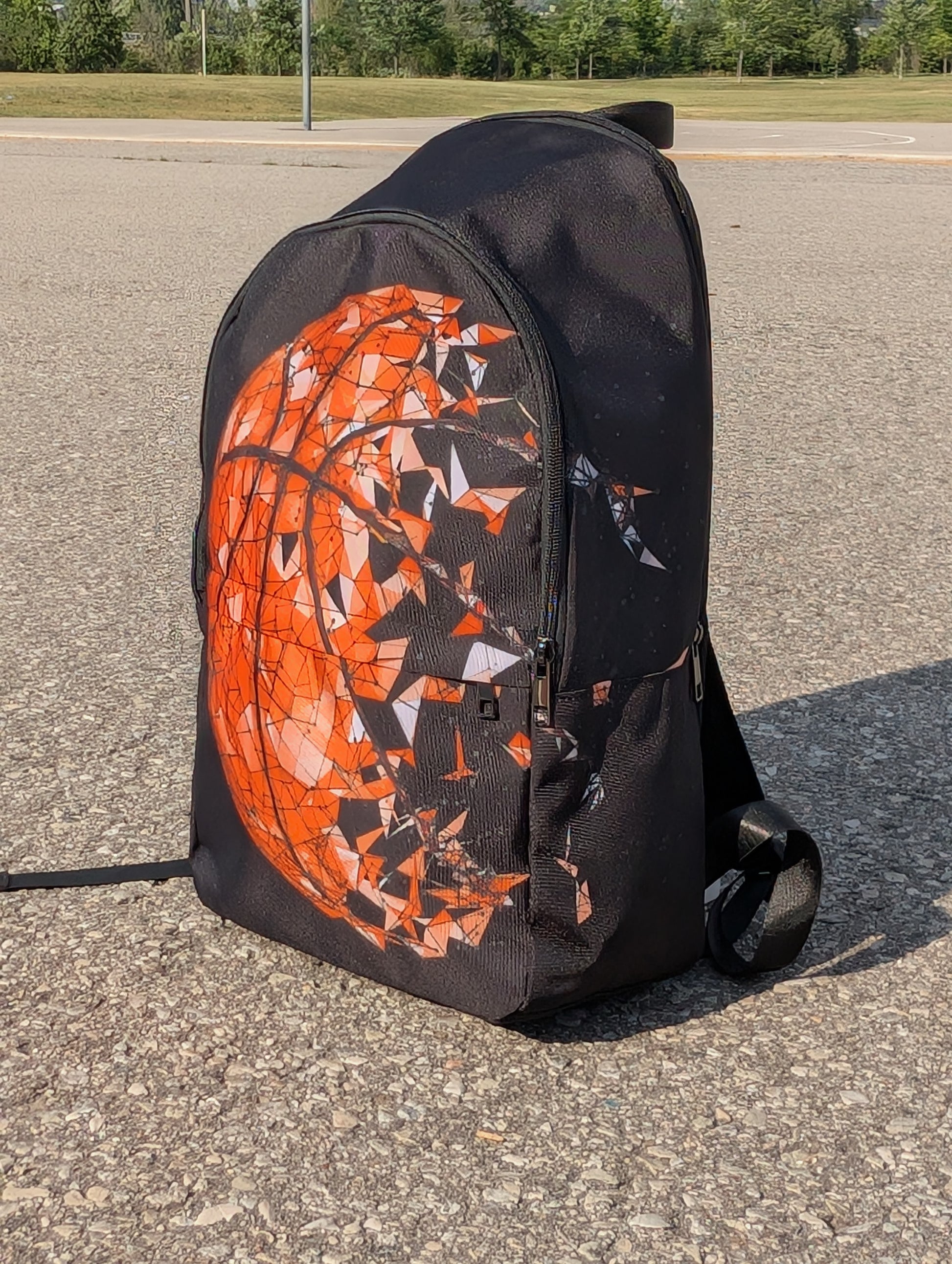 angled view of a backpack with basketball picture that breaks apart in pieces to the right on a basketball court.
