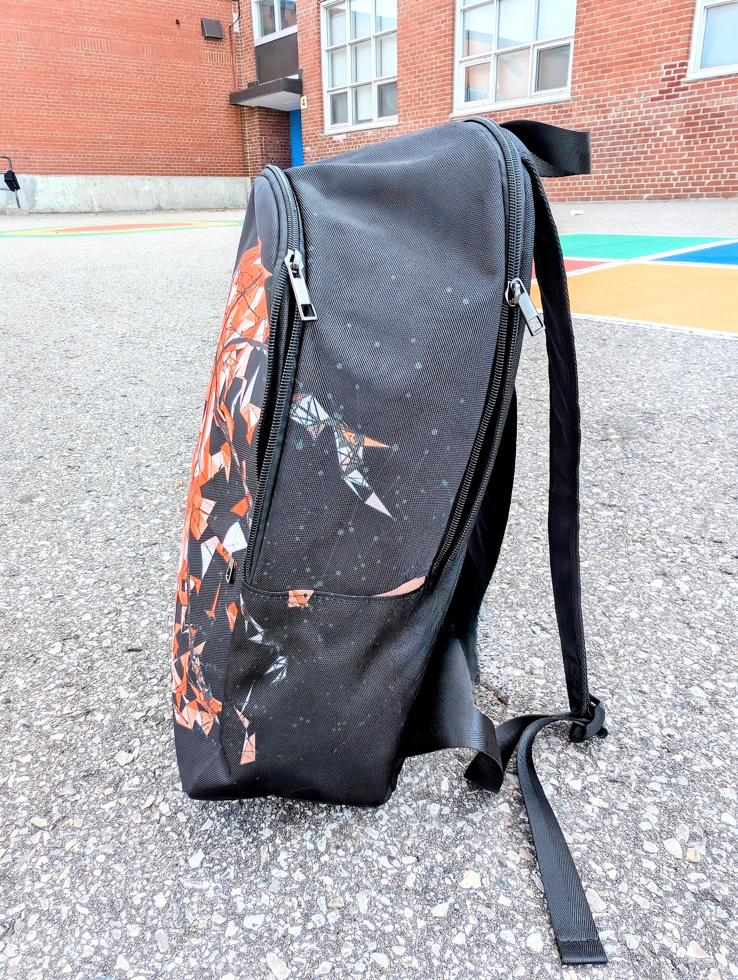 Side view of a backpack with basketball picture that breaks apart in pieces to the right on a basketball court.