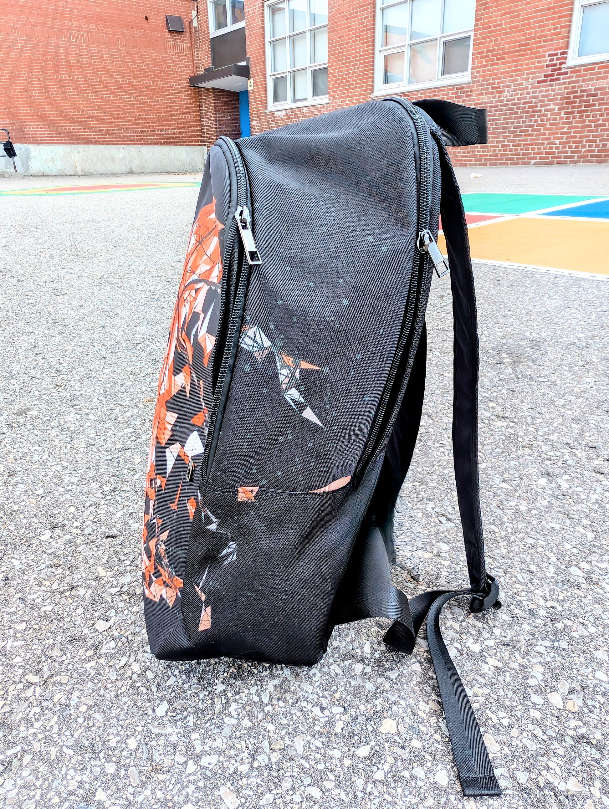 Side view of a backpack with basketball picture that breaks apart in pieces to the right on a basketball court.