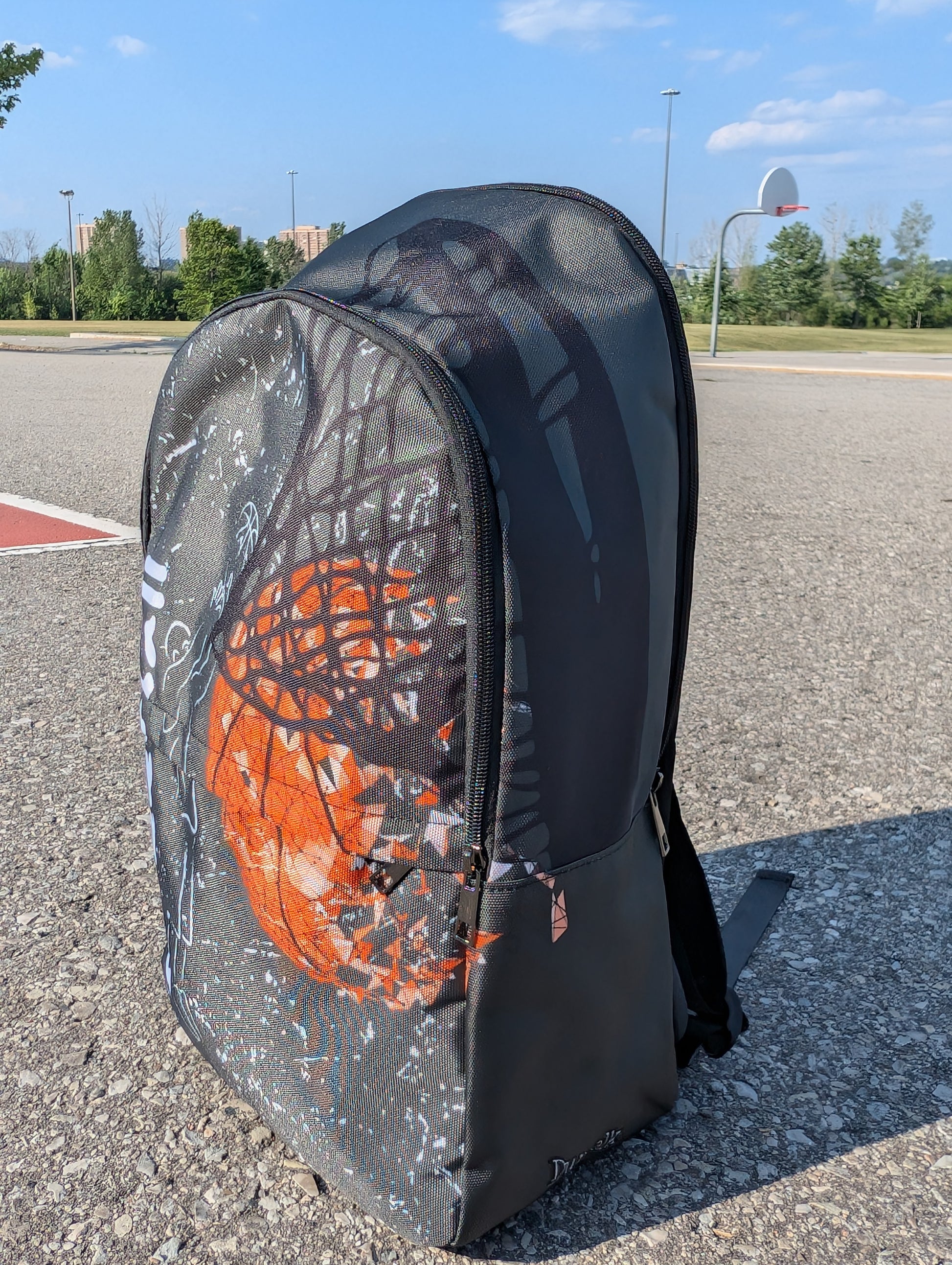 Side view backpack with chalk drawing of a man shooting a basketball beside the word streetball.  Beside it a large basketball going through a net on a basketball court