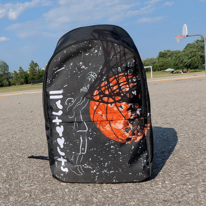 Front view backpack with chalk drawing of a man shooting a basketball beside the word streetball.  Beside it a large basketball going through a net on a basketball court