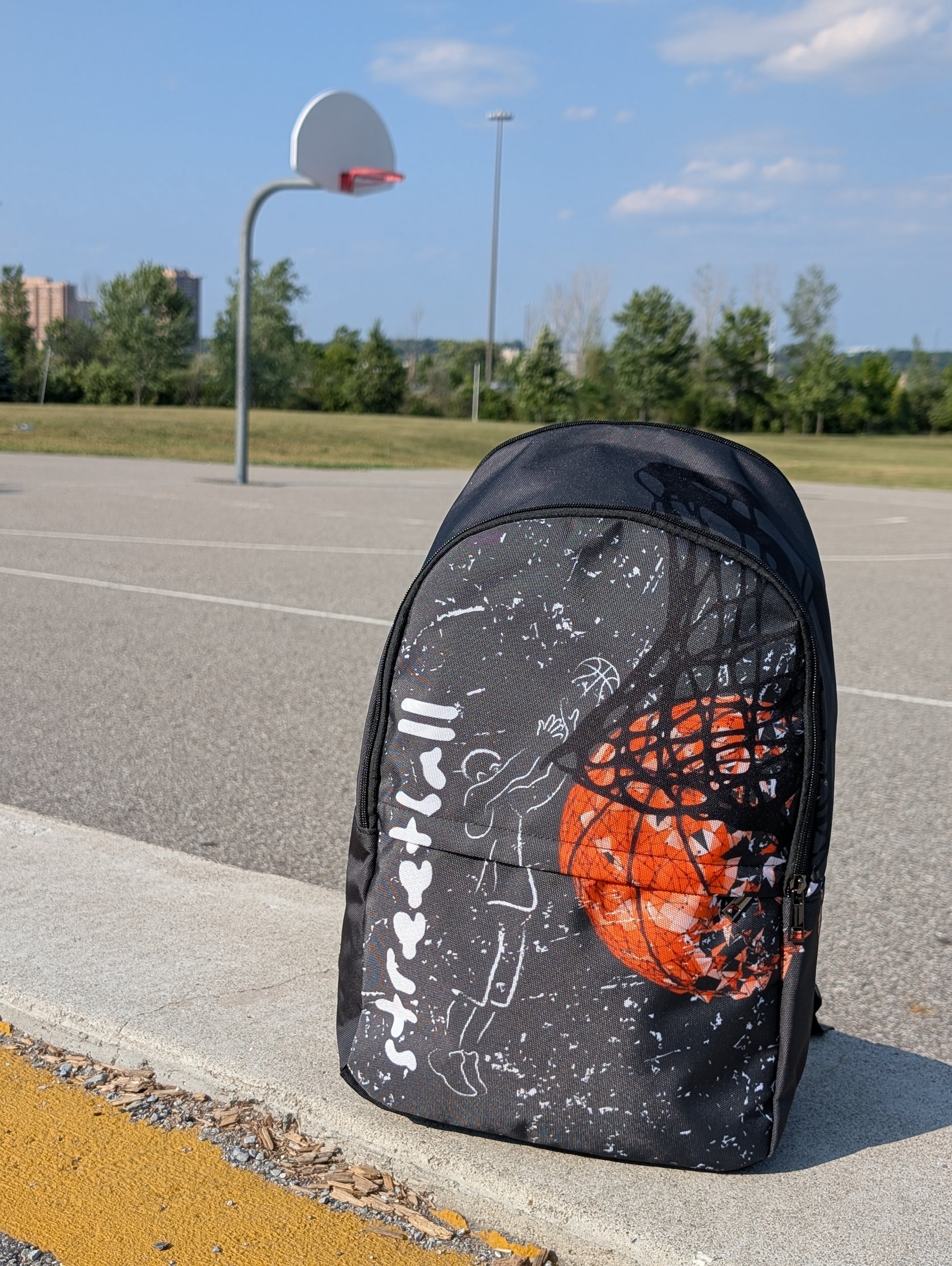 Front view backpack with chalk drawing of a man shooting a basketball beside the word streetball.  Beside it a large basketball going through a net on a basketball court.