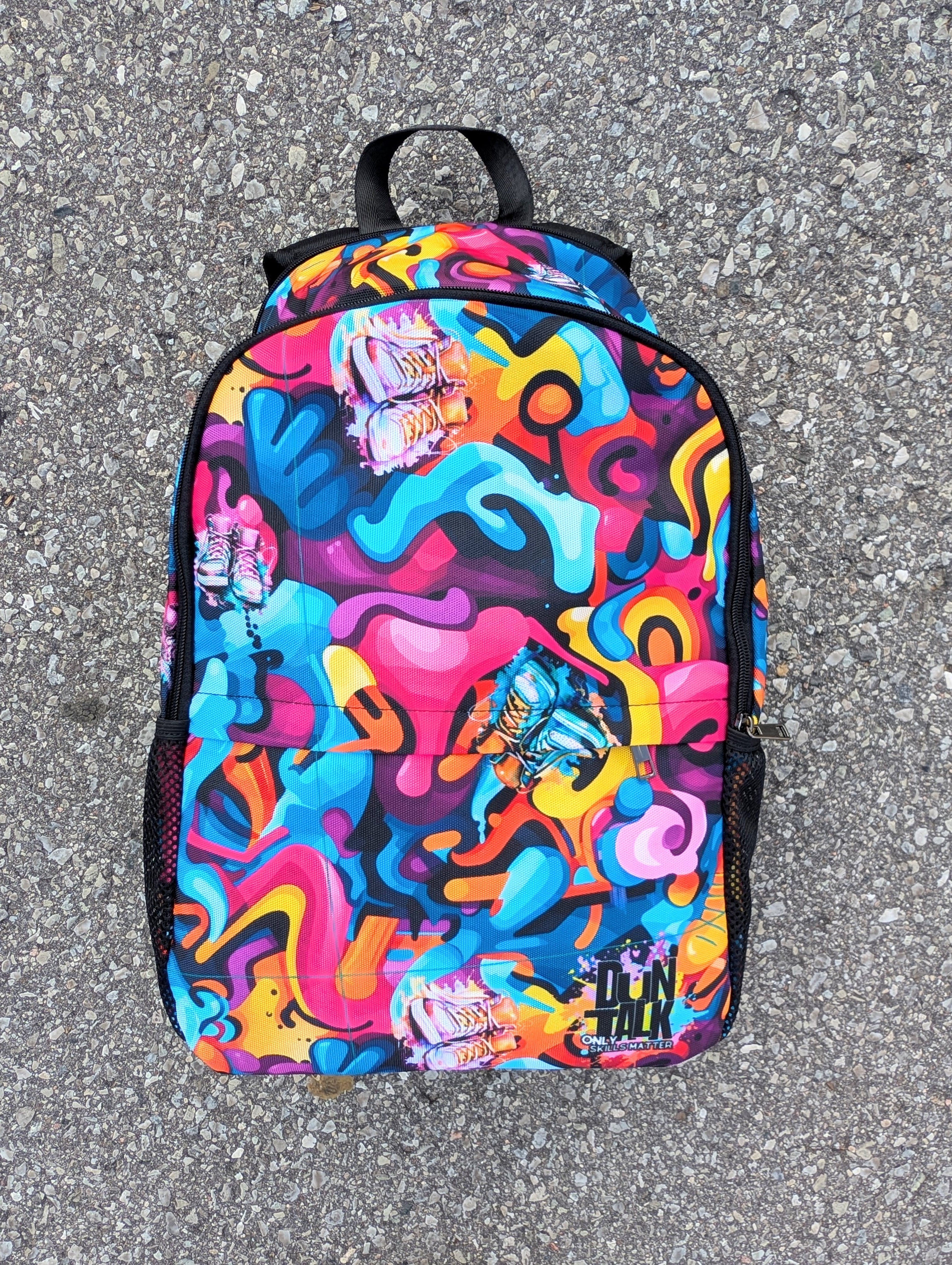 Colorful backpack with abstract design on a gray pavement background