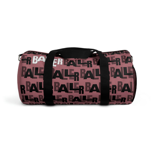 Pink duffle bag with "baller" written in black text around the bag. "Baller" is written once in white on the top left of the bag. Two hand straps